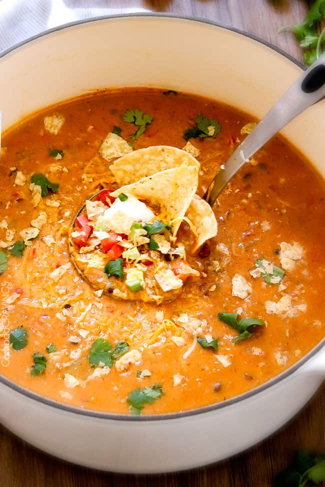 a large ladle full of creamy Taco Soup in a white soup pot garnished with cilantro
