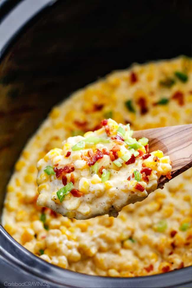 a serving spoon of southern creamed corn in the slow with green onions and bacon
