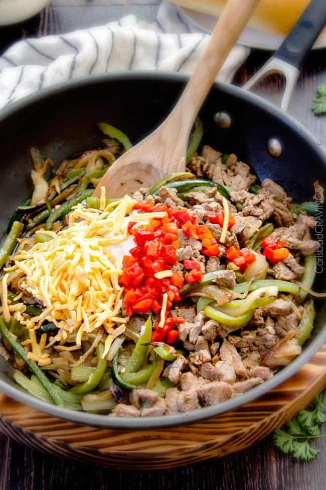 showing how to make authentic Philly Cheese steak sandwich recipe by adding cheese and pimientos to the steak and bell peppers