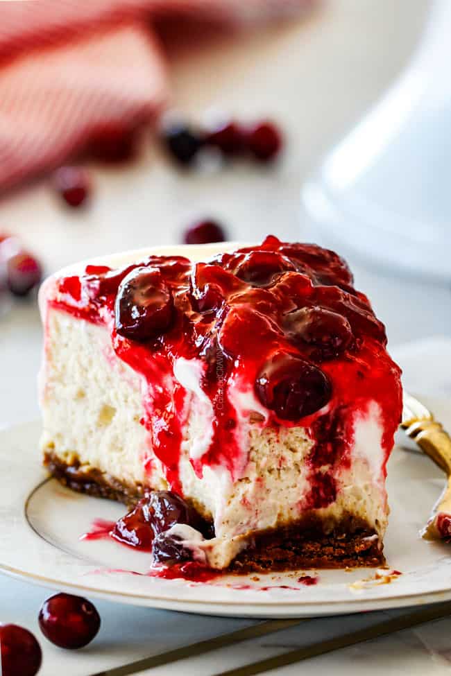 A slice of Cranberry Eggnog Cheesecake with a bite missing. 