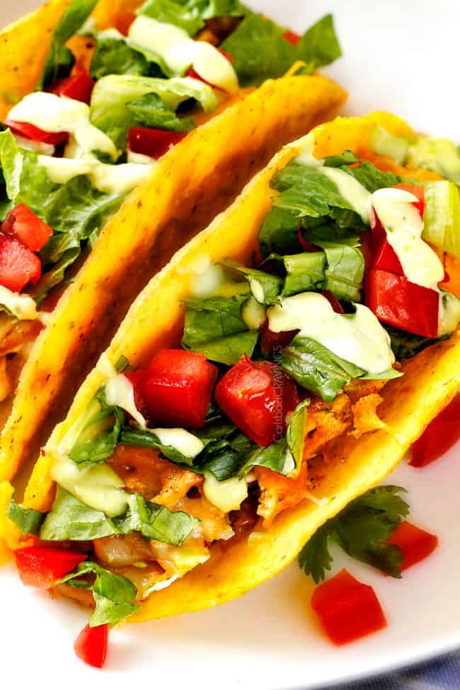 Close up view of Ranch Chicken Tacos piled with refried beans, cheese.