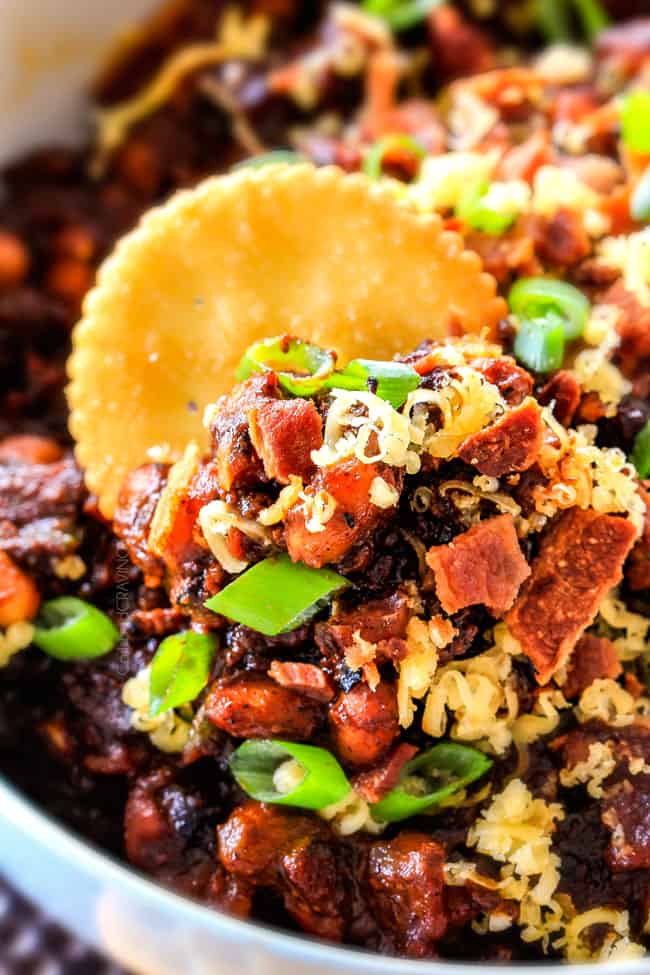 Extreme close up view of Boston Baked Bean Dip piled with bacon, cheese, sour cream, green onions.