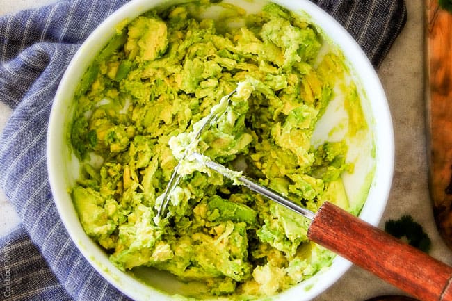 showing how to make avocado hummus by adding avocados to a bowl and mashing them