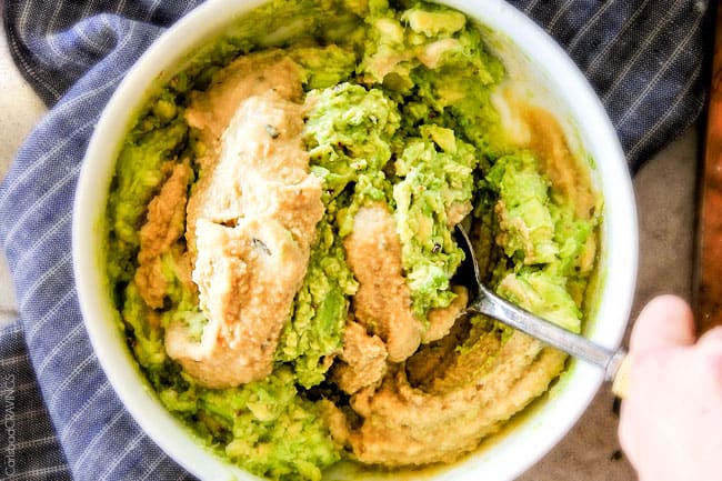 showing how to make avocado hummus by stirring in hummus