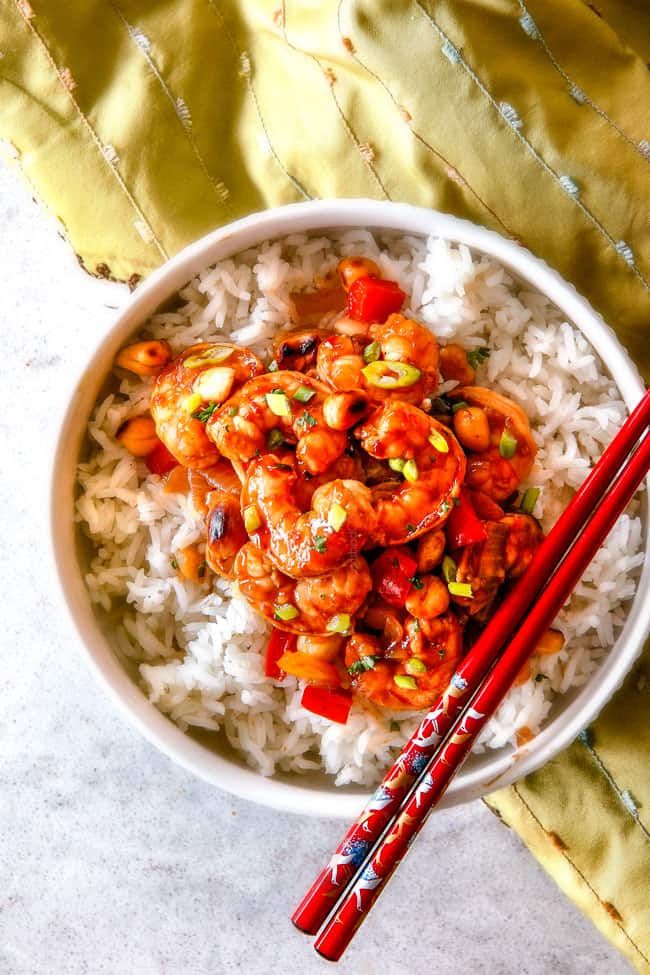 top view of easy Kung Pao Shrimp in a white bowl with red chopsticks
