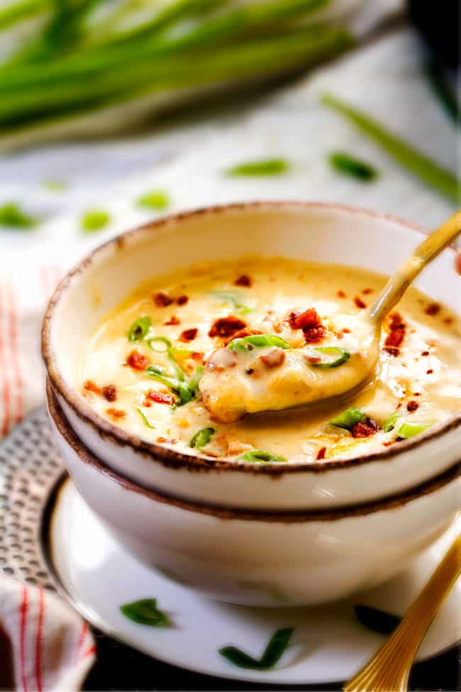 far away shot of crockpot potato soup in a bowl with a gold spoon