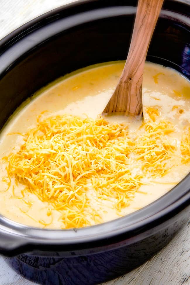 showing how to make crockpot potato soup by adding cheese to soup in slow cooker