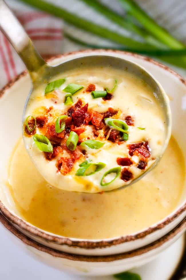 holding up a ladle of cream crockpot potato soup with bacon and green onions