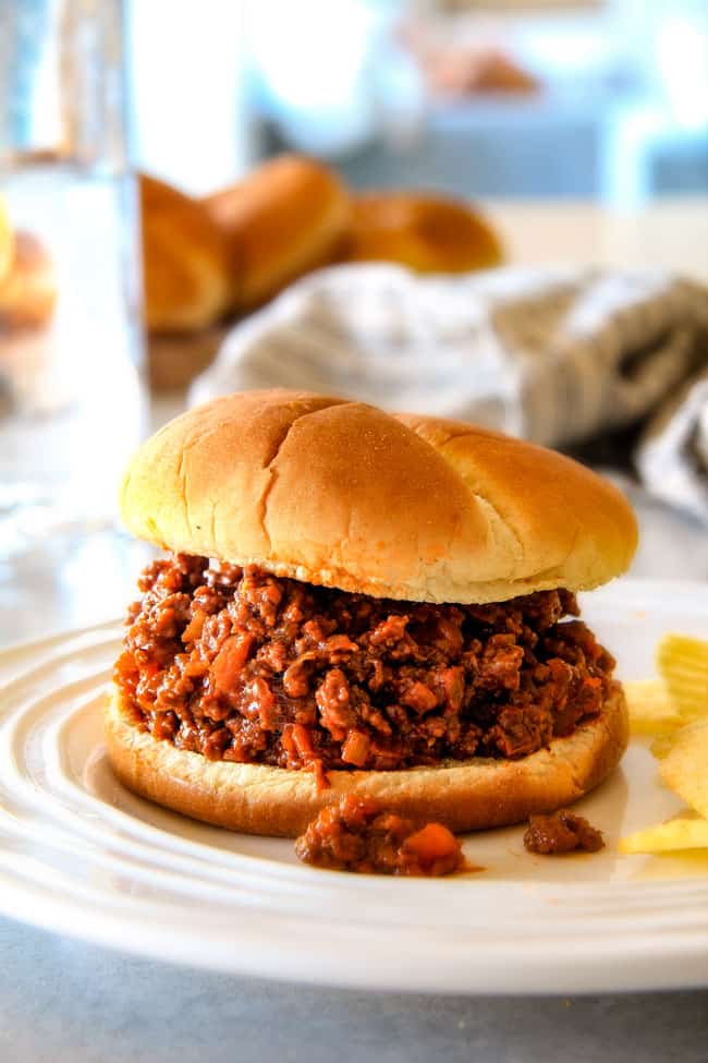 up close of homemade sloppy joes on a whtie plate with potato chips