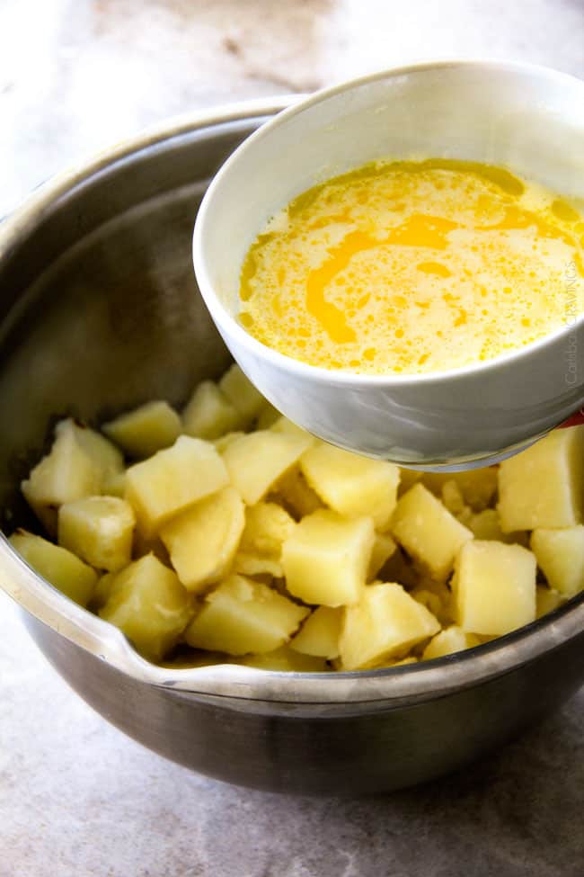 showing how to make mashed potato recipe by pouring butter into a mixing bowl with cooked potatoes