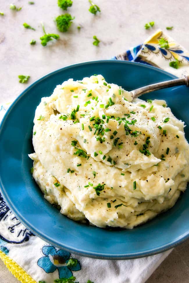 showing how to make mashed potatoes by garnishing with fresh chives in blue bowl