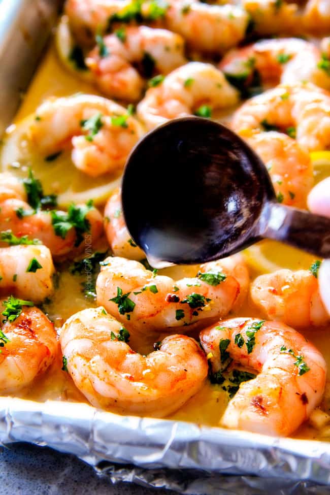 Pouring butter over top of Roasted Lemon Garlic Butter Shrimp and Asparagus