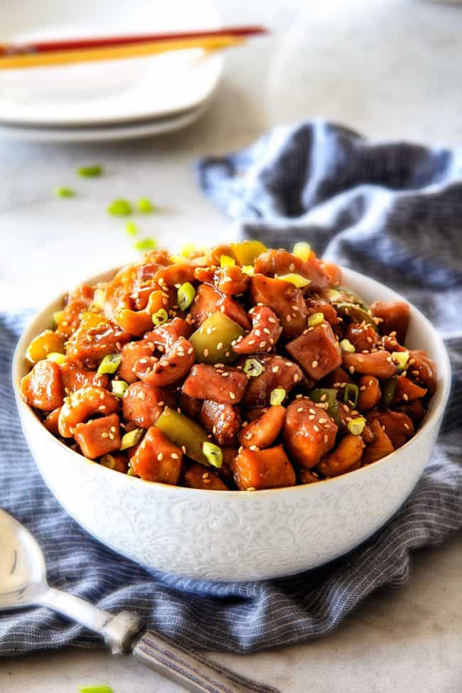 healthy Cashew Chicken in a white bowl with bell peppers, cashews and sesame seeds