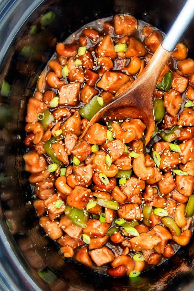 top view of easy Crock Pot Cashew Chicken in the slow cooker with a wooden spoon