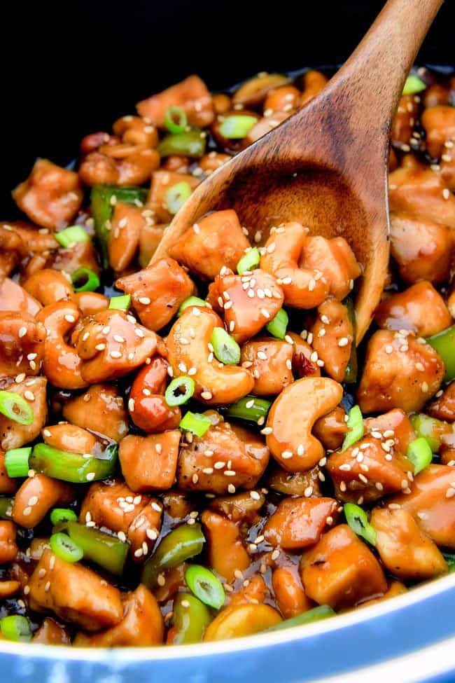up close of a wooden spoon serving Slow Cooker Chinese Cashew Chicken recipe with vegetables
