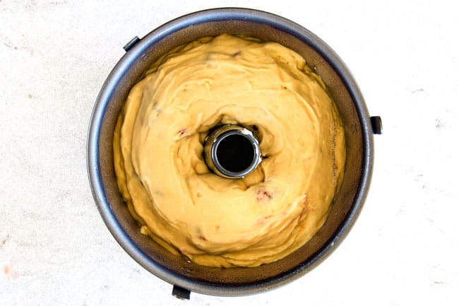showing how to make Cream Cheese Coffee Cake by adding batter on top of cream cheese in bundt pan
