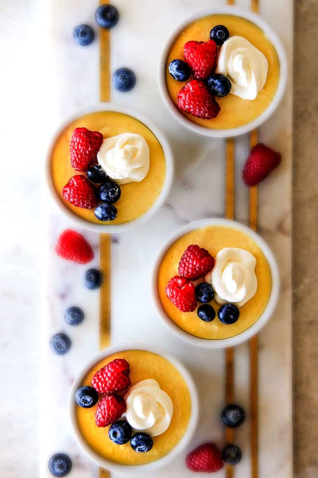 Top view of Lemon Pots de Creme with berries and cream on top. 
