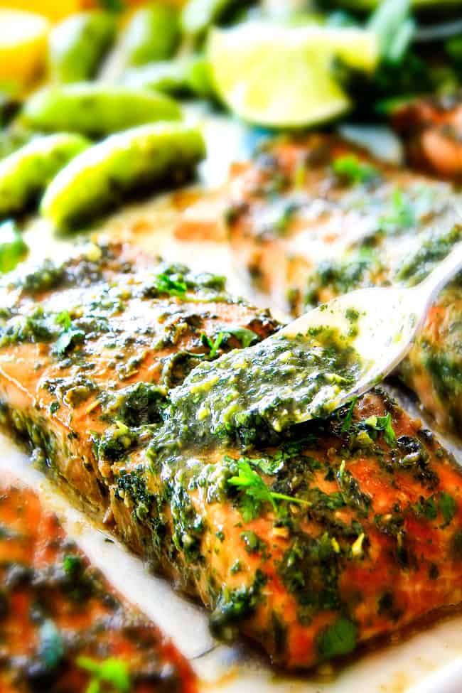 Cloe view of Asian Chimichurri Salmon on a pan with vegetables pouring butter herbs on top. 
