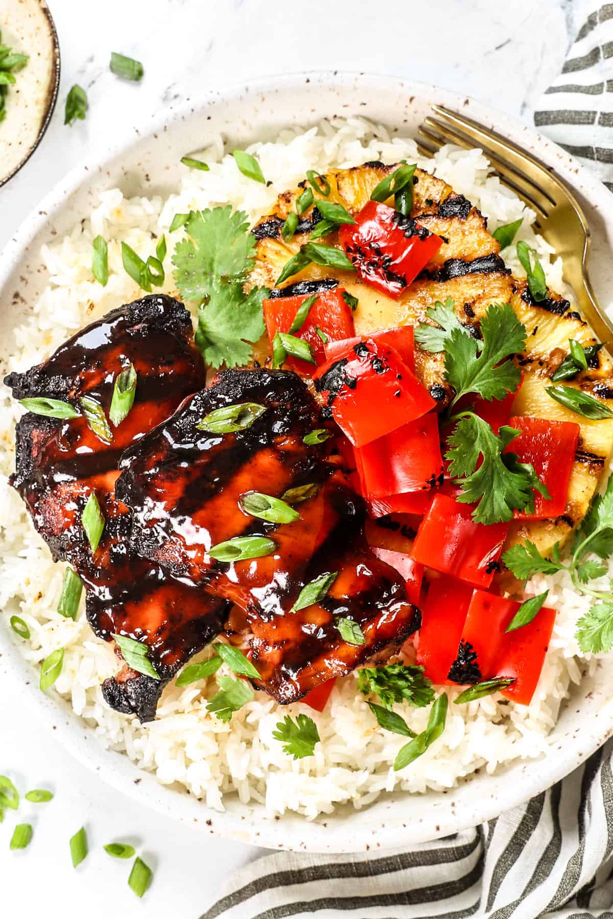 showing what to serve with huli huli chicken by adding to rice with pineapple and grilled vegetables