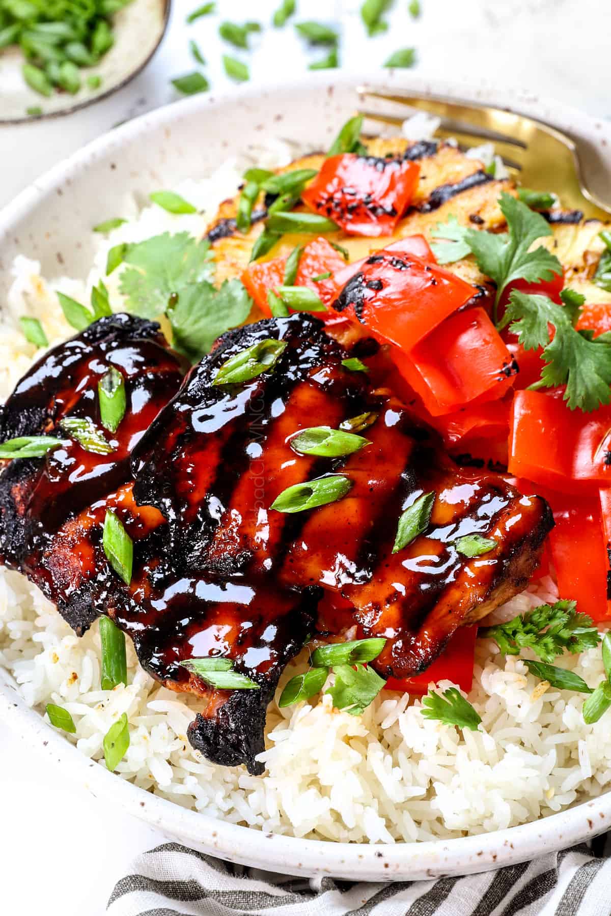 Huli Huli Chicken recipe being served in a bowl with rice, pineapple, and grilled bell peppers