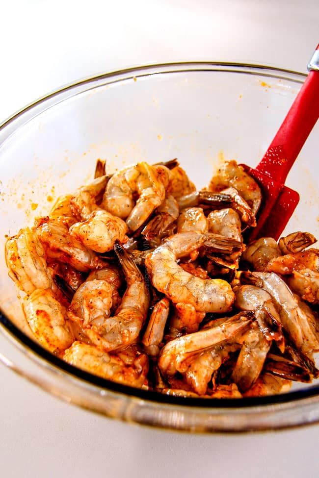 showing how to make  Old Bay Shrimp by mixing shrimp with seasonings in a bowl