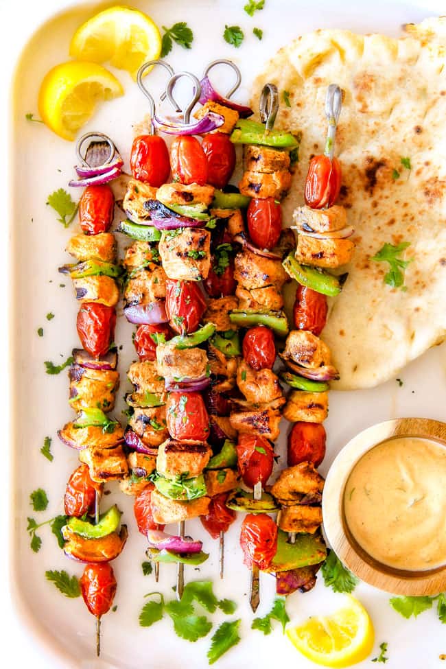 Tandoori Chicken Kabobs next to bread and dipping sauce. 
