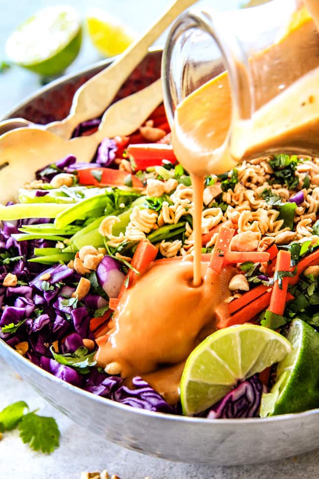 Crunchy Asian Salad with Sriracha Peanut Dressing being poured over top. 