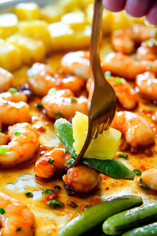 a fork taking a bite of teriyaki shrimp and pineapple