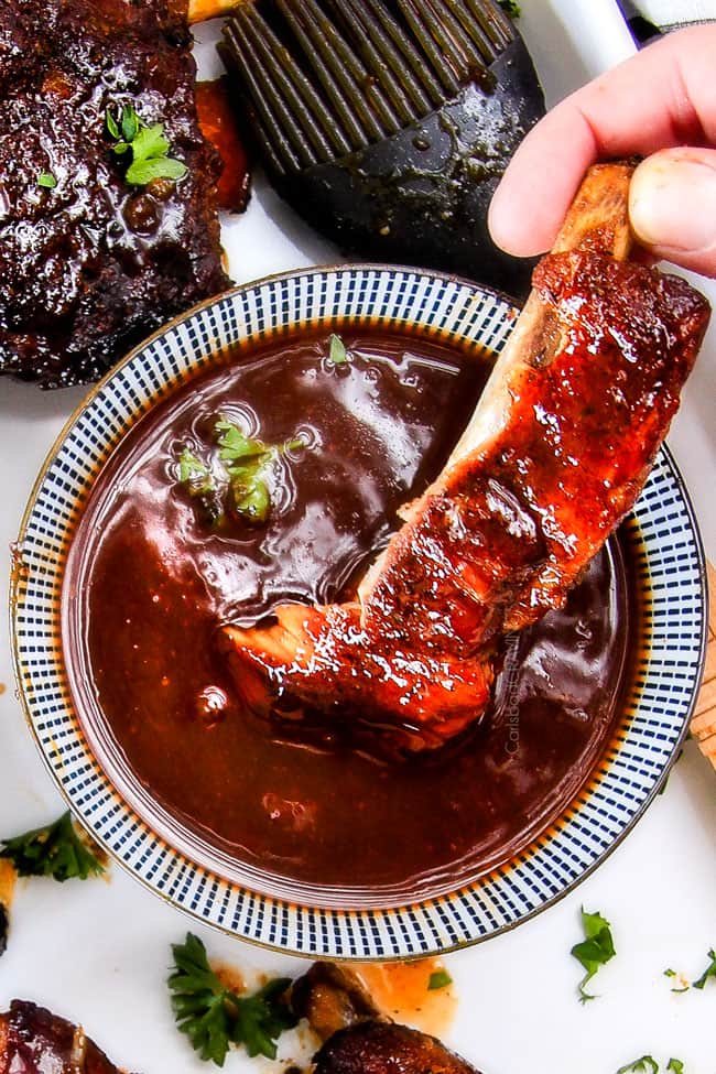 Dipping a Slow Cooker Honey Buffalo Ribs in sauce. 