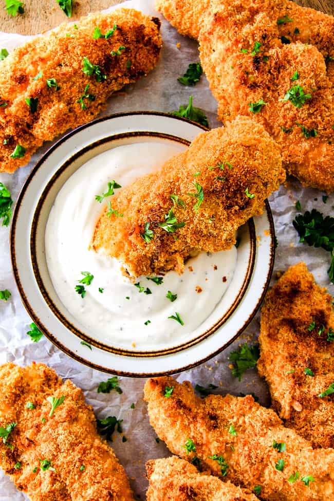 Baked Cheddar Ranch Chicken Tenders dipping in sauce. 
