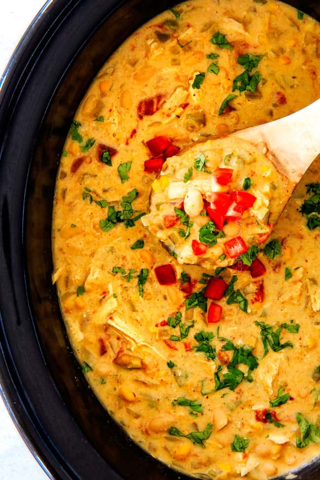 Crockpot Creamy White Chicken Chili being served with a wood spoon. 