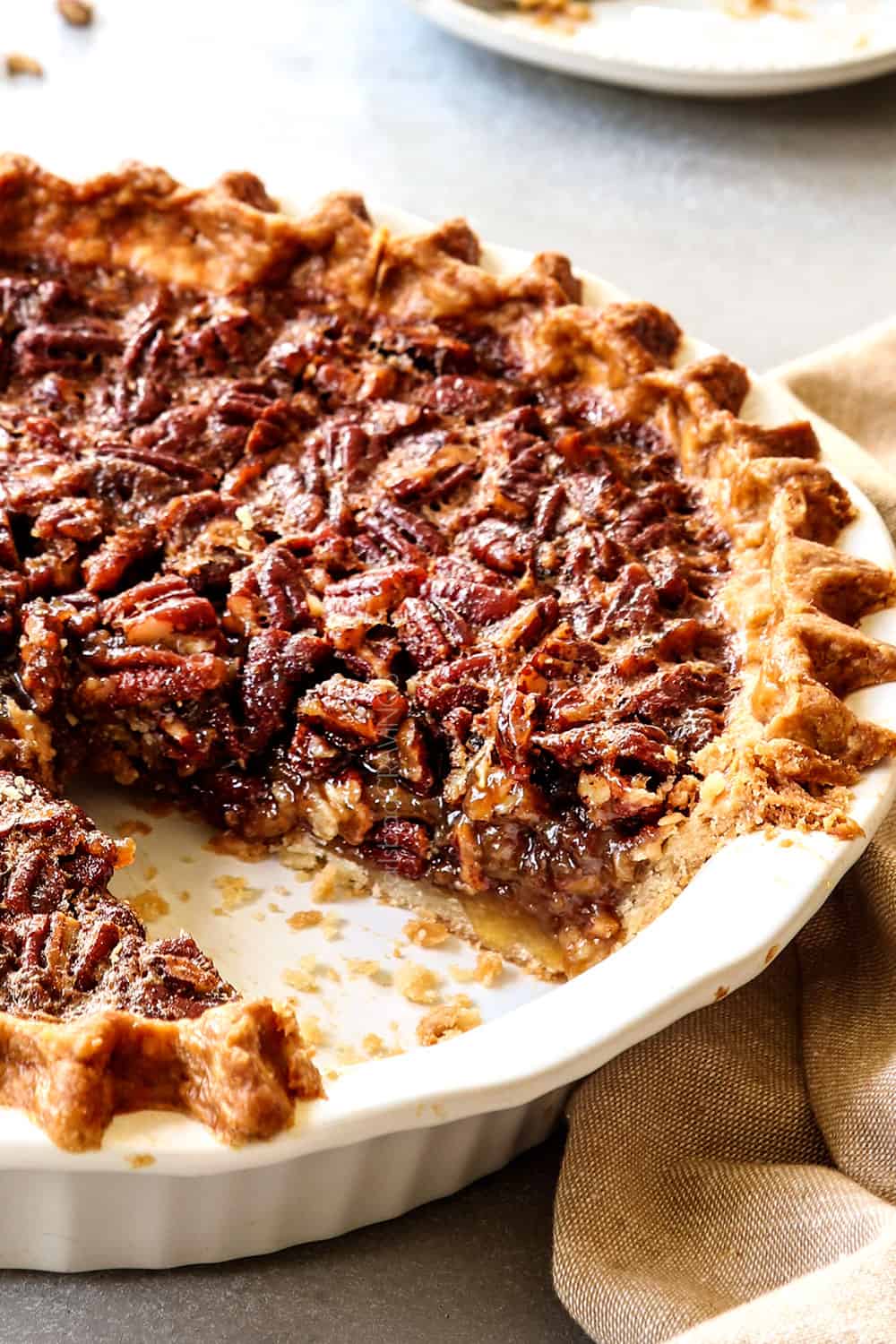 up close side view of pecan pie recipe in the pie plate with a piece missing showing the texture if the filling