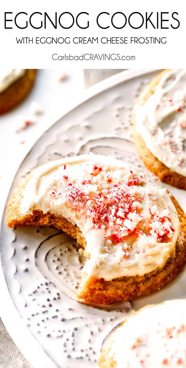 close up of an eggnog cookie topped with eggnog frosted and crushed candy canes. A bite is missing. 