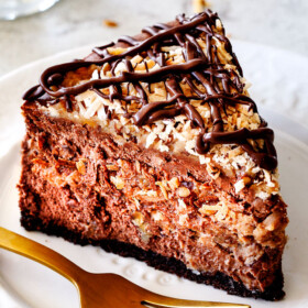 German Chocolate Cheesecake AKA the best German Chocolate anything! The rich and creamy chocolate cheesecake has a hidden layer of traditional caramel-eaque sweet and crunchy Coconut Pecan Frosting and another layer on top! This cheesecake is to live for!