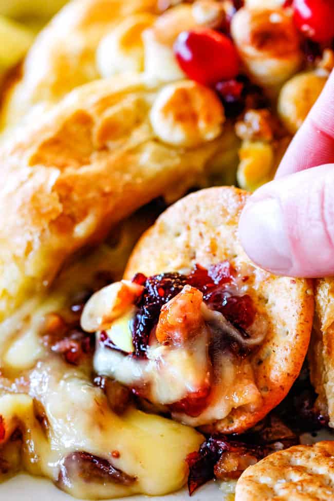 up close of oozing baked brie in puff pastry with jam, cranberries and pecans