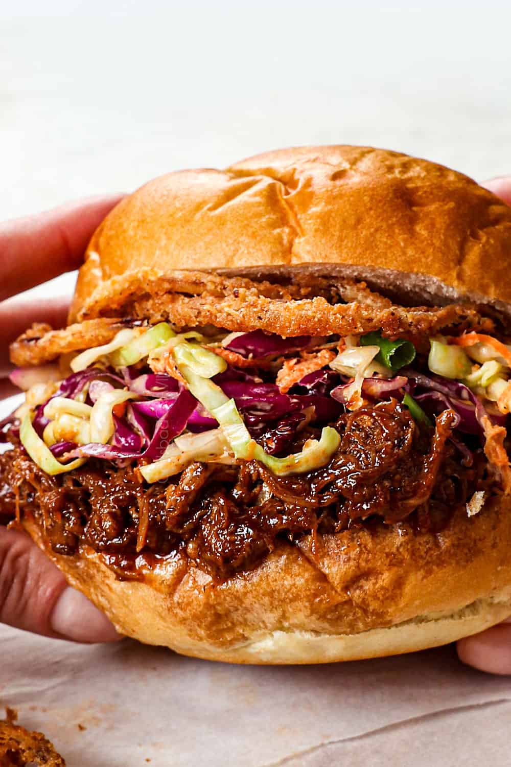 showing how to serve BBQ pulled pork by making BBQ pulled pork sandwiches with coleslaw and fried onion rings