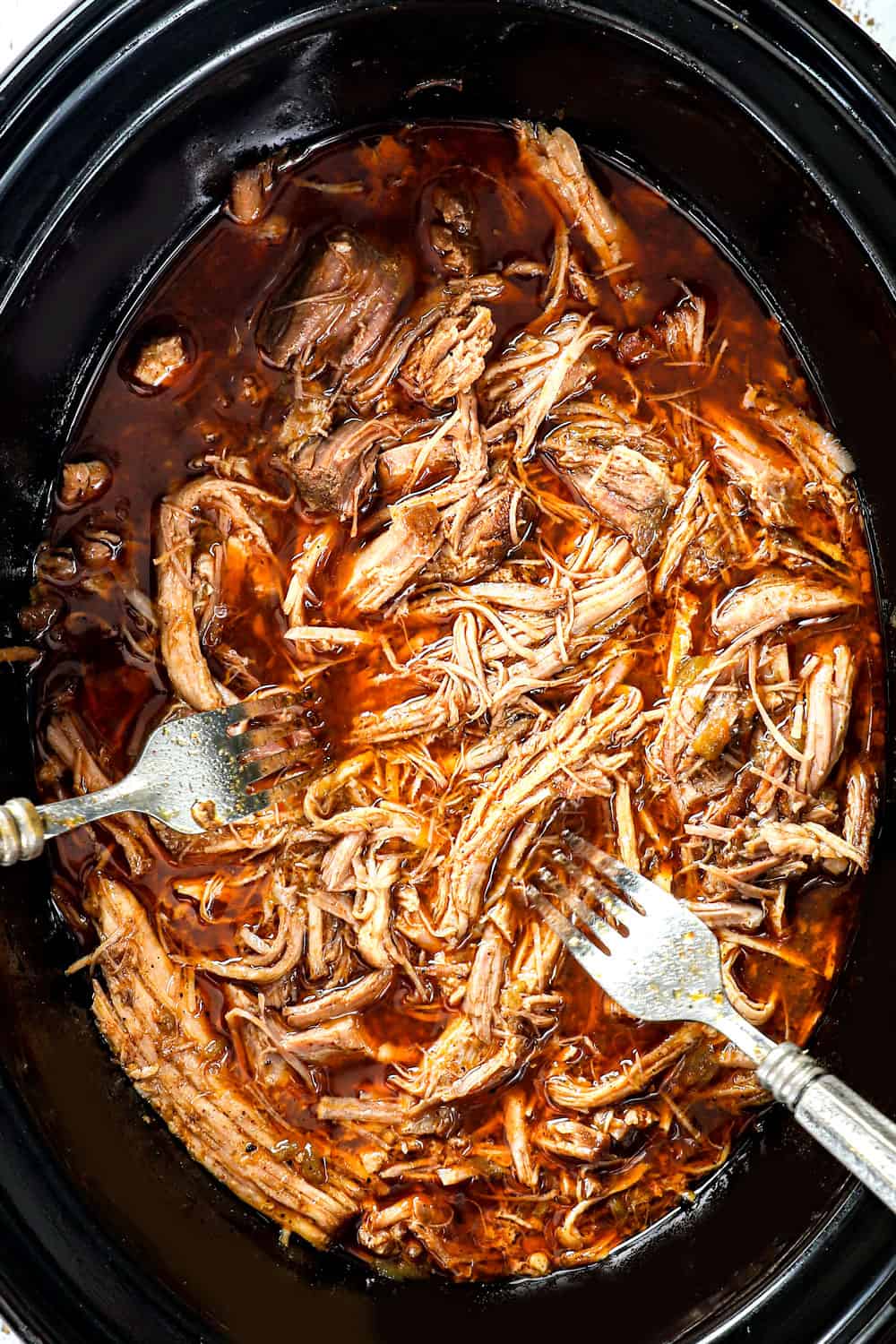 showing how to make BBQ Pulled Pork recipe by shredding the pork and allowing it to braise in the juices