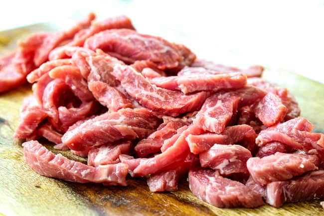 thinly sliced flank steak on a cutting board showing how to make ginger beef