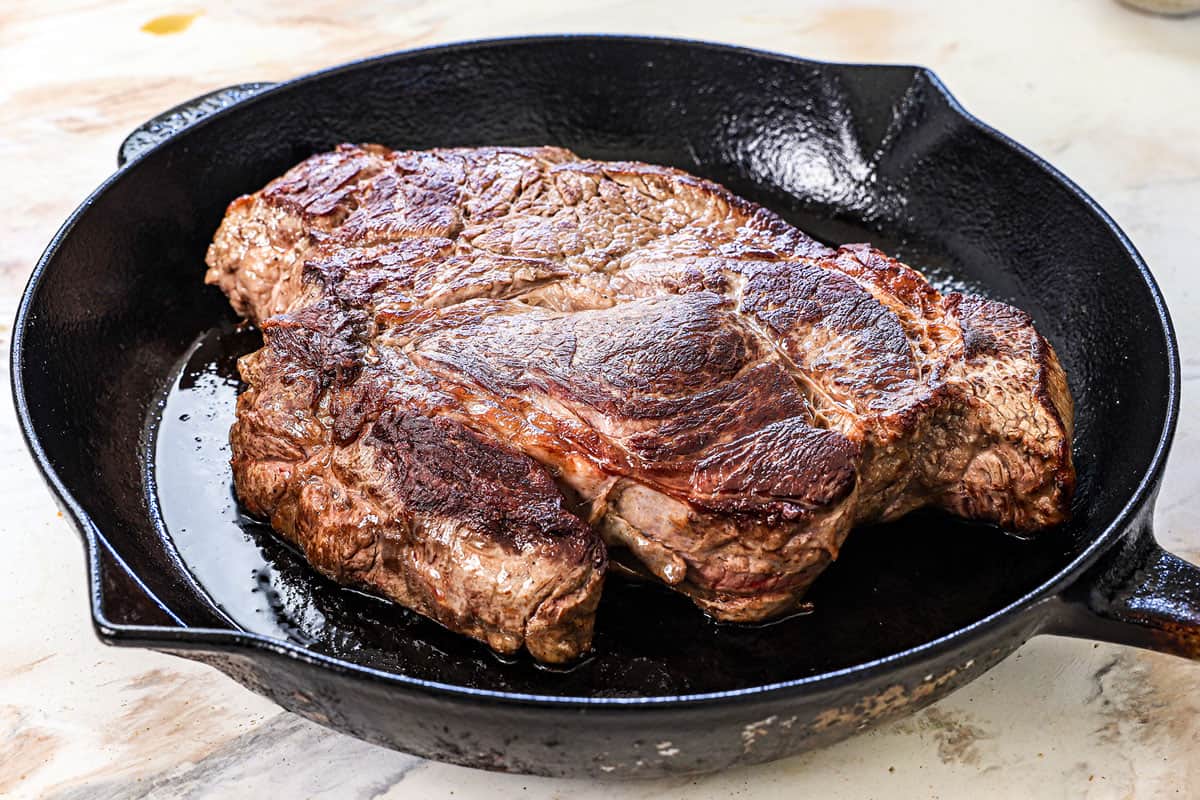showing how to cook a roast in the oven by searing the roast in a cast iron skillet