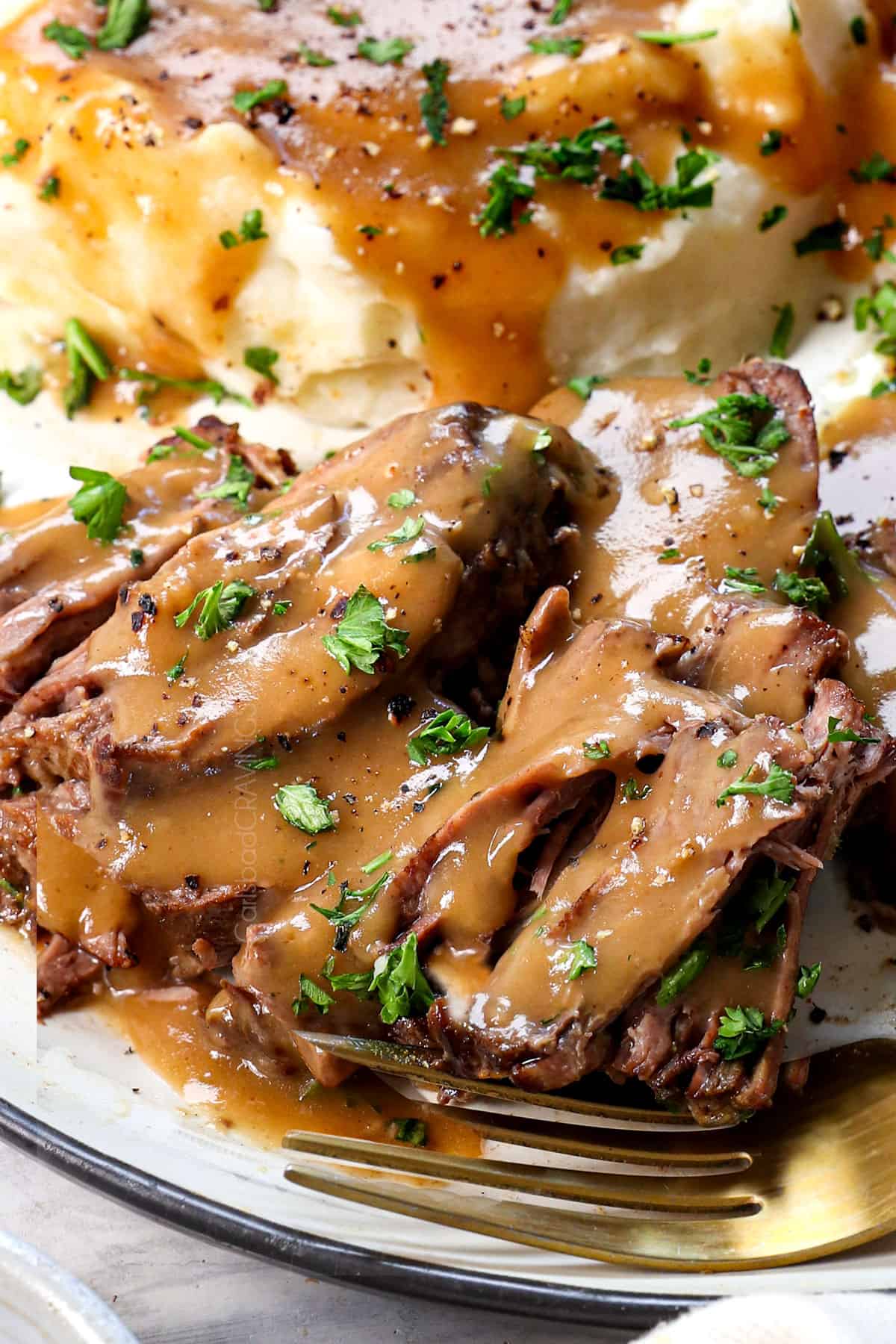 pot roast being served on a plate with gravy
