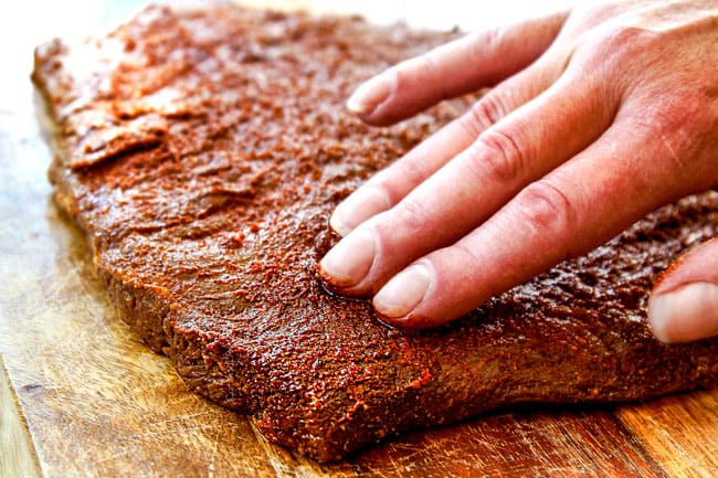 showing how to make grilled steak fajitas by massaging wet rub into the marinated steak