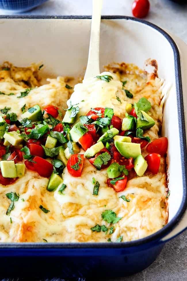 showing how to serve Green Chile Chicken Enchiladas by scooping out a cheesy spatula full