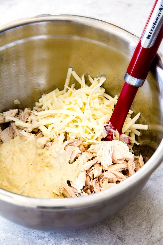 showing how to make Green Chile Chicken Enchiladas by mixing chicken and cheese together in a bowl