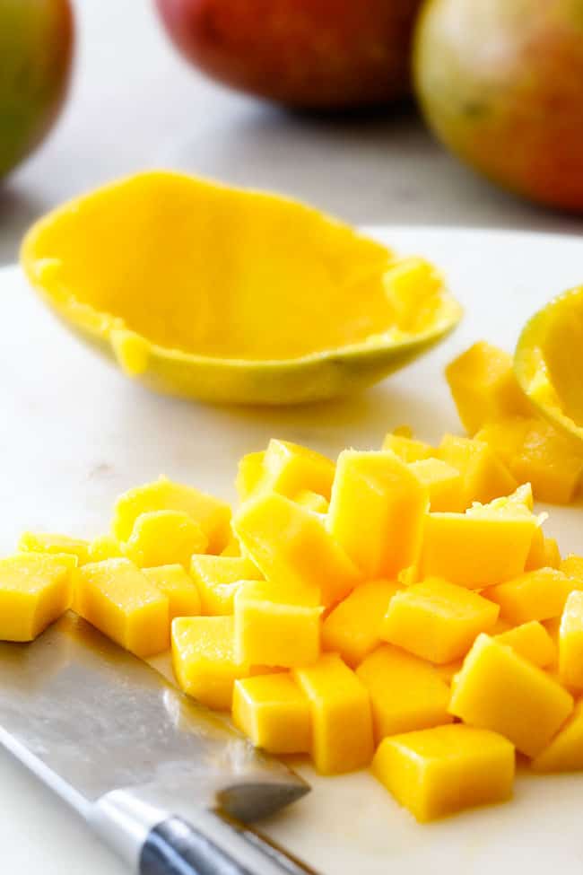 Showing how to Cut a mango with mango cubes on a white cutting board after cutting