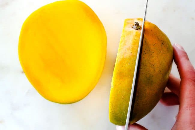 How to Cut A Mango showing cutting mango around stem on a white cutting board