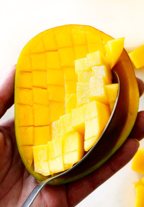 How to Cut A Mango showing scooping cubes of cut mango out with a spoon