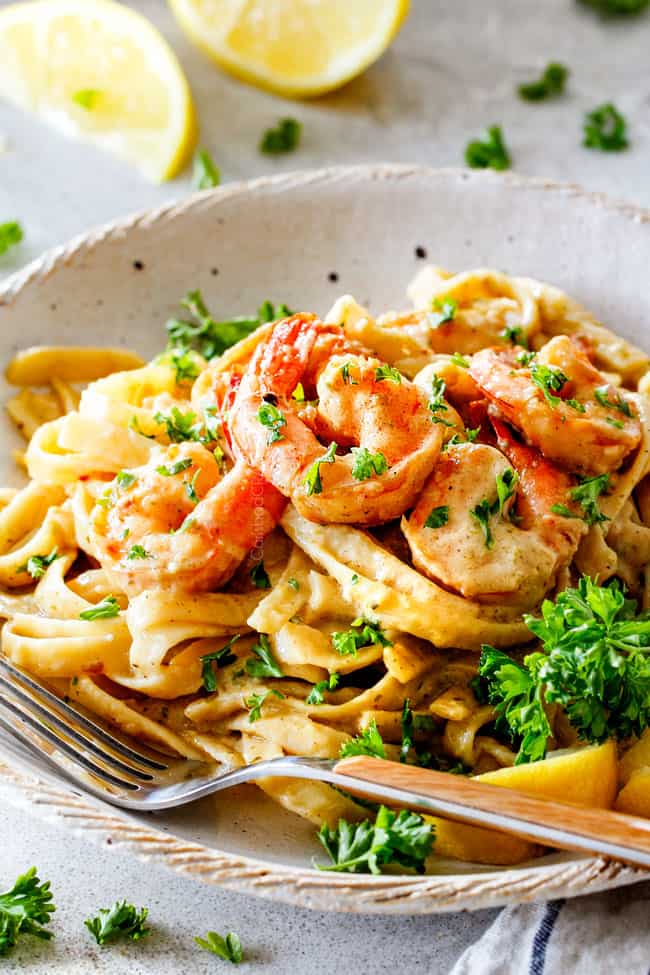 side view of lemon garlic shrimp pasta in white plate with fork