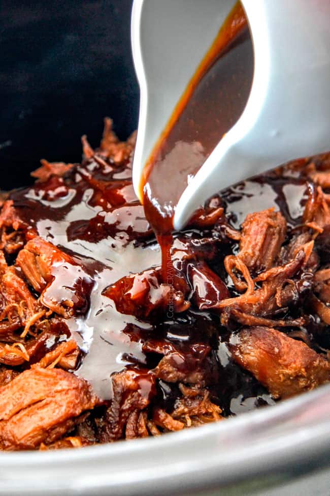 Asian sauce being drizzled on pulled pork in the crock pot