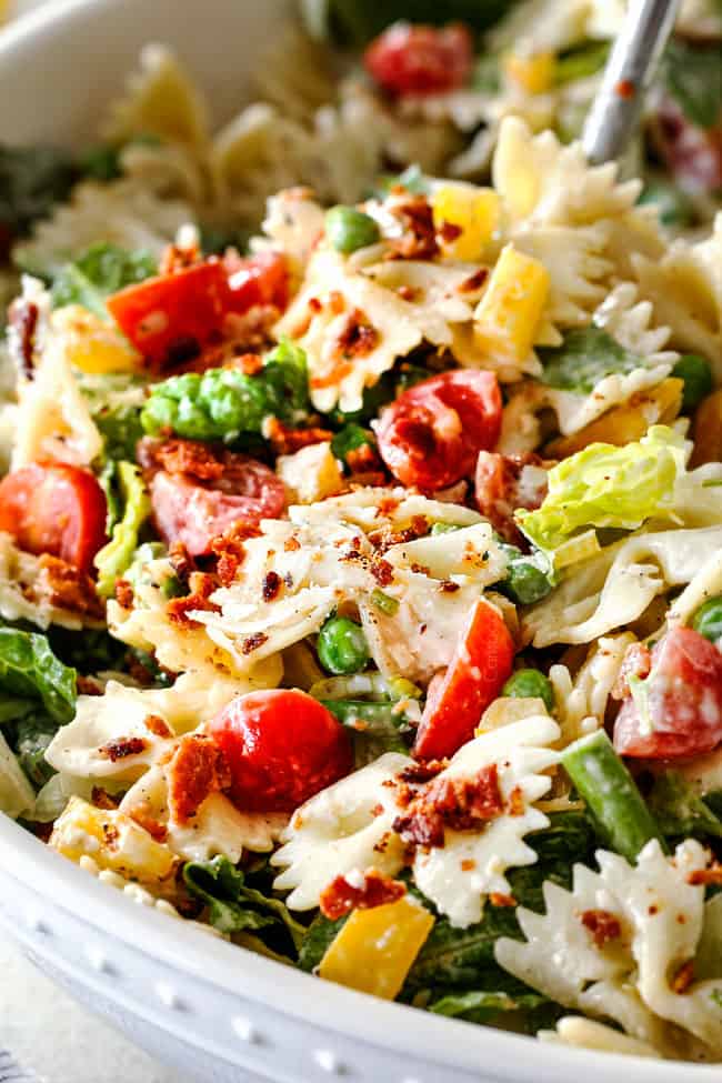 Up close side shot of easy BLT Pasta Salad recipe in a white bowl with one fork spearing pasta