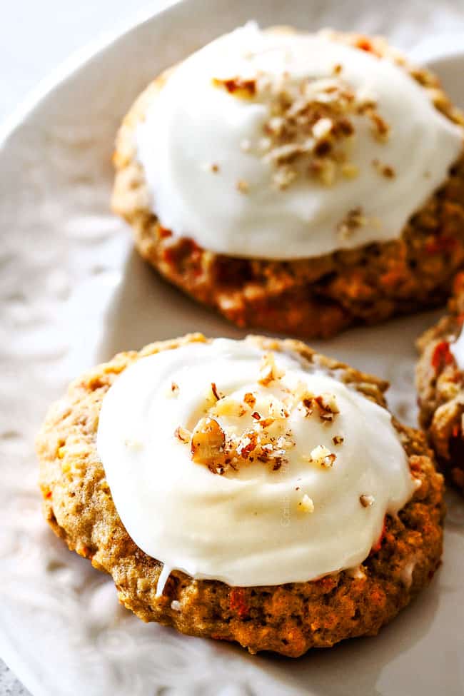 Up close of moist carrot cake cookies with cream cheese frosting on a white plate